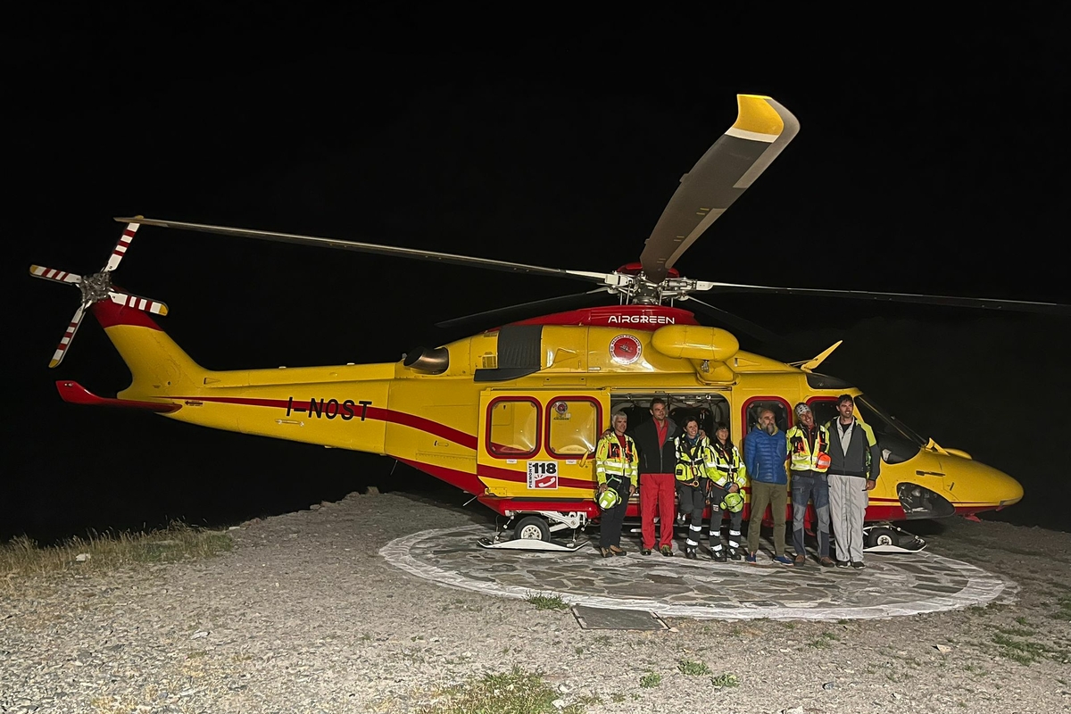 un elicottero fermo sull'elisuperficie del rifugio, nella notte del collaudo. Davanti al velivolo alcune persone.