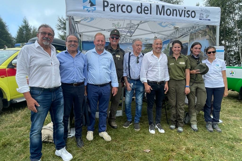 Nove persone davanti al gazebo del Parco del Monviso durante il concerto di ferragosto Monviso Unesco: il terzo da sinistra è il presidente Dario Miretti, il quarto da destra è il Vicepresidente della Regione Piemonte Fabio Carosso.