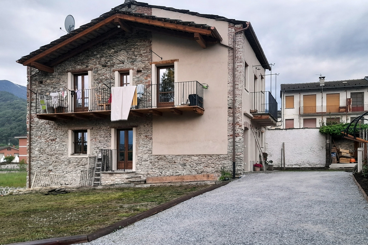 nella parte laterale sinistra della foto si vede un caseggiato in pietra con un balcone e sulla destra un ampio spazio ghiaiato di accesso alla casa