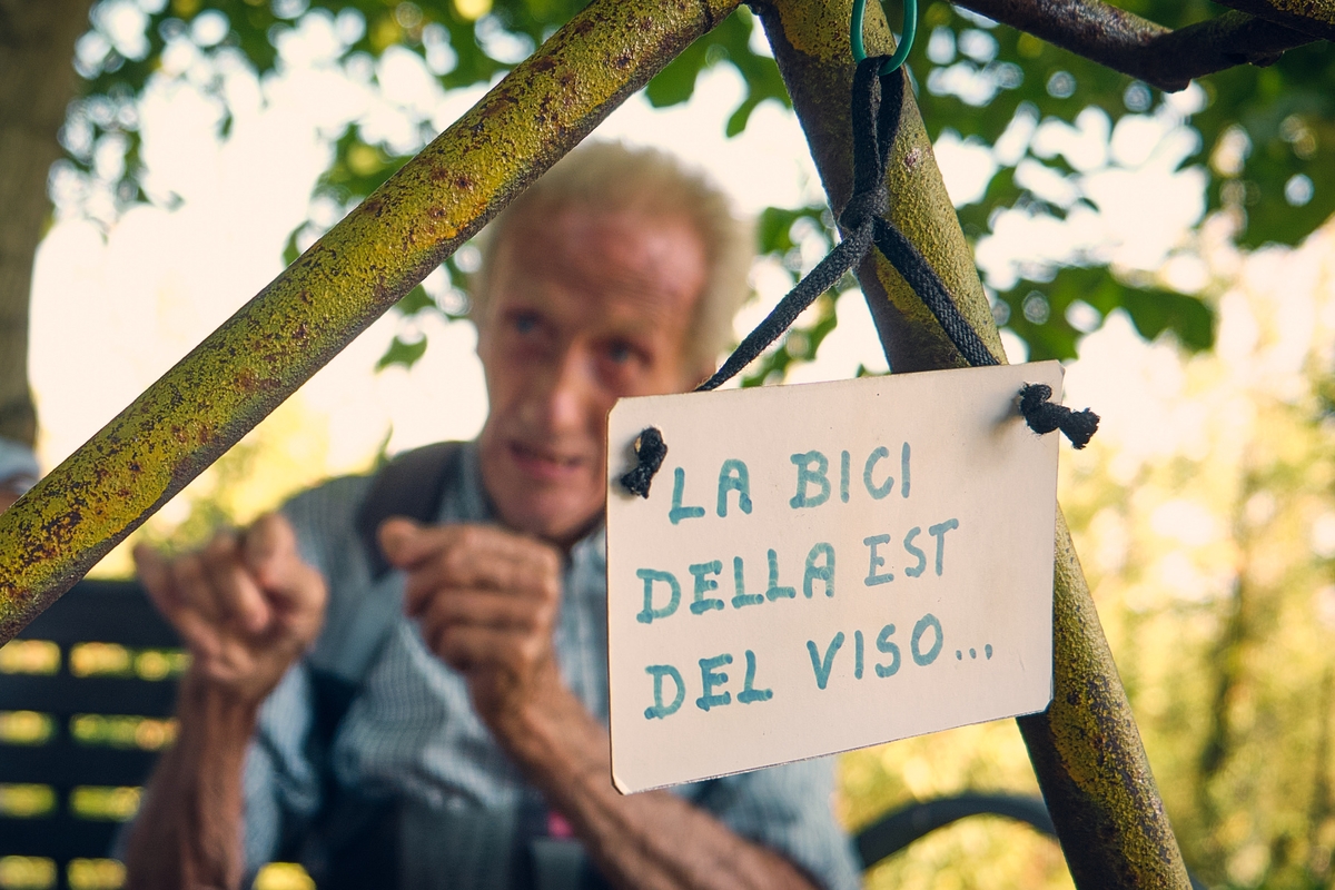 In primo piano si vede una parte del telaio della bicicletta, con un cartellino appeso su cui si legge la bici della Est del Viso...; in secondo piano e sfocato c'è Clemente Berardo.