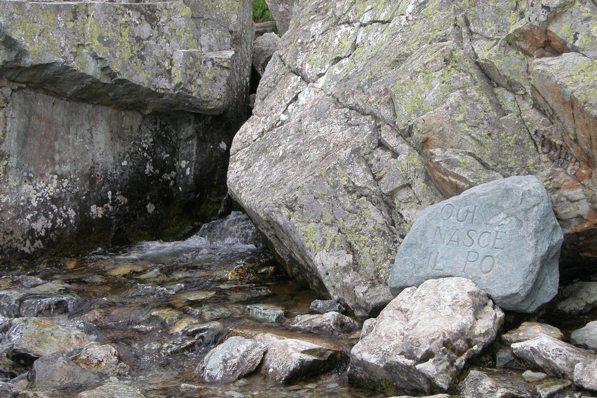 le sorgenti del po: sotto grandi rocce macchiate dai licheni sgorga l'acqua che si trasforma subito in torrente. sulla destra una roccia riporta la scritta qui nasce il Po