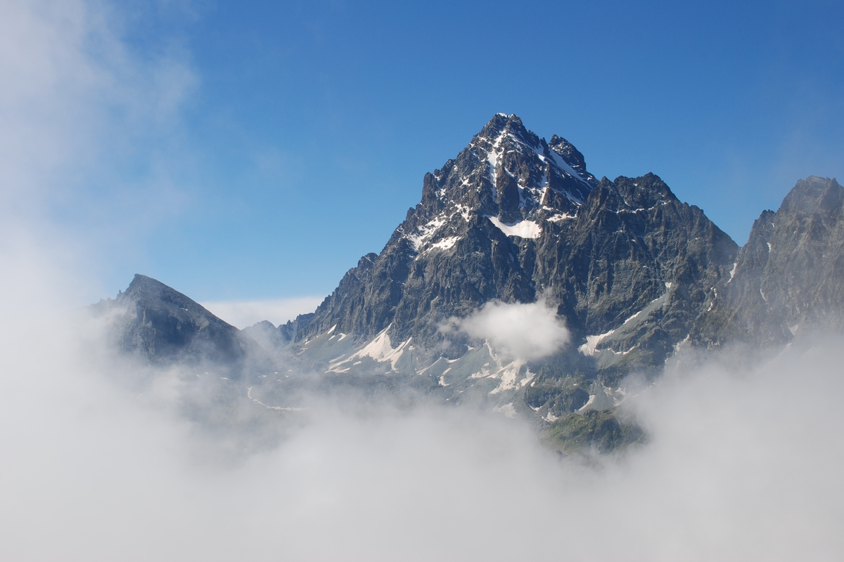 la cima del monviso spruzzata d neve spunta tra la nebbia