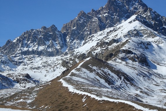 Il monviso innevato e in primo piano cresta e pianoro ancora con colori autunnali