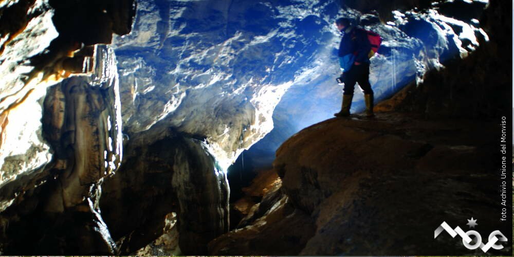 uno speleologo all’interno della grotta: con una torcia illumina le caratteristiche concrezioni calcaree dell’ambiente ipogeo