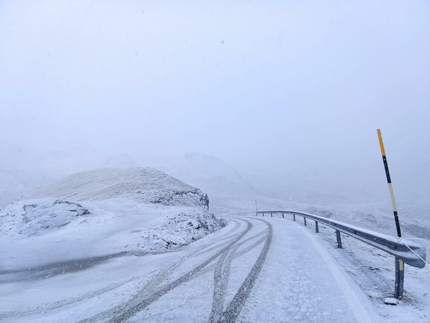 una strada con una leggera spolverata di neve, immersa in un ambiente reso grigio dalla nebbia e dalle precipitazioni.