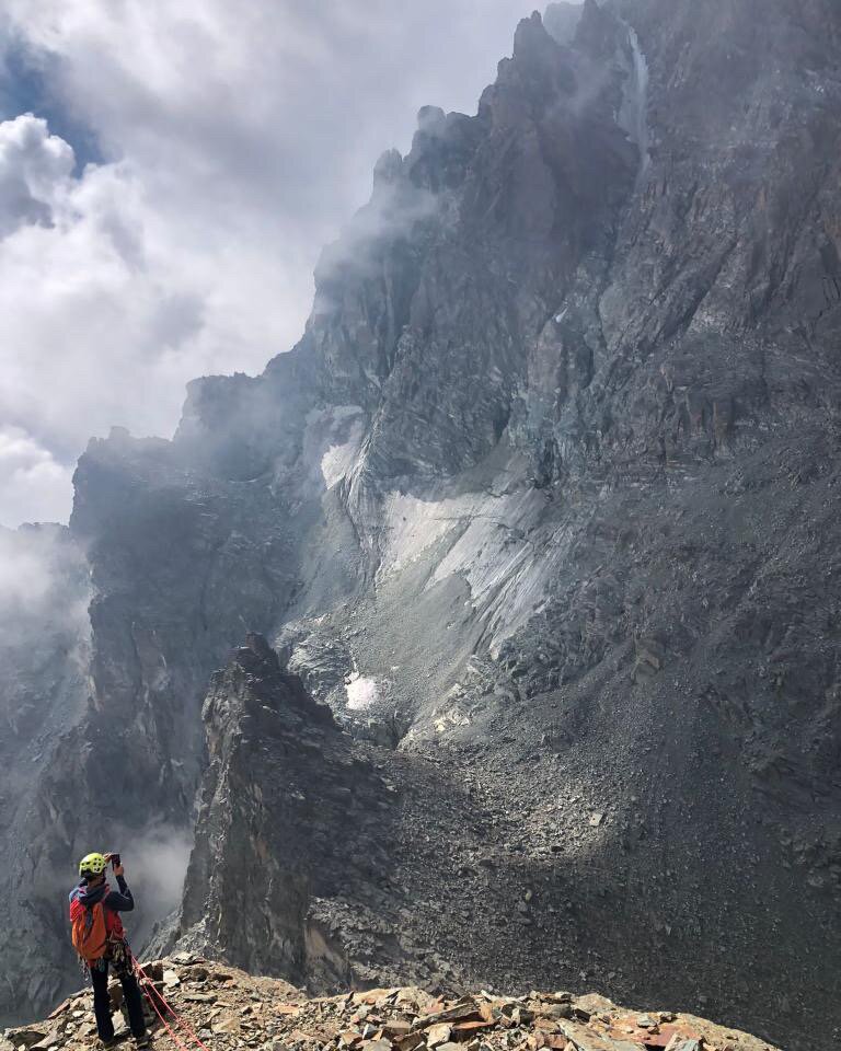 un alpinista, in basso a sinistra nella foto, guarda con un binocolo il ghiacciaio Coolidge al centro dell'immagine.