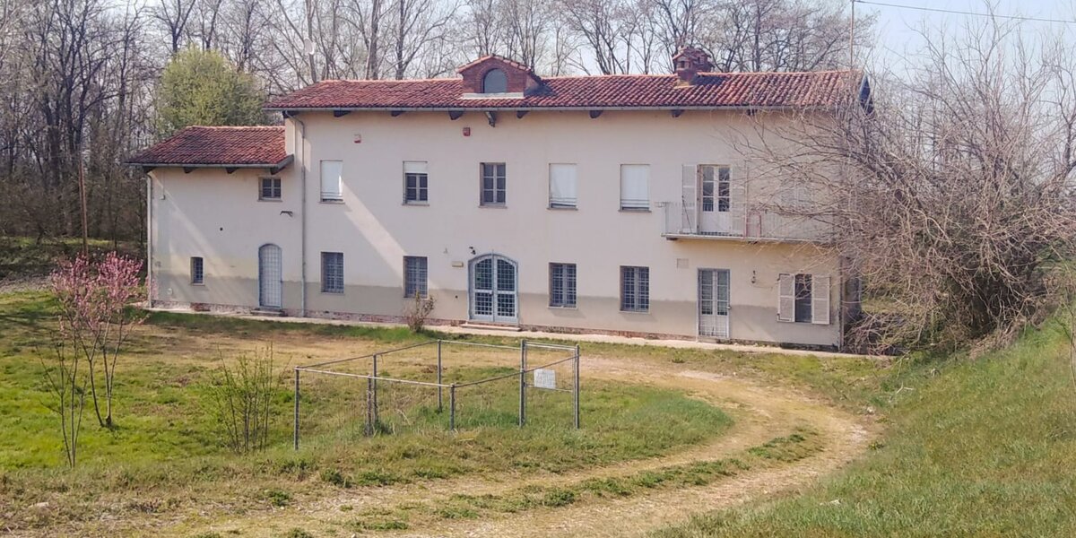 Caseggiato a due piani con pareti giallo chiaro e tetto in tegole rosse. intorno prati e alberi