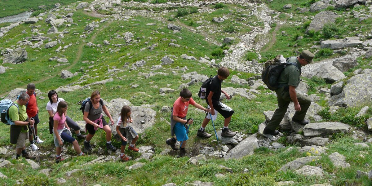 Un guardiaparco guida un gruppo di escursionisti su un sentiero in montagna