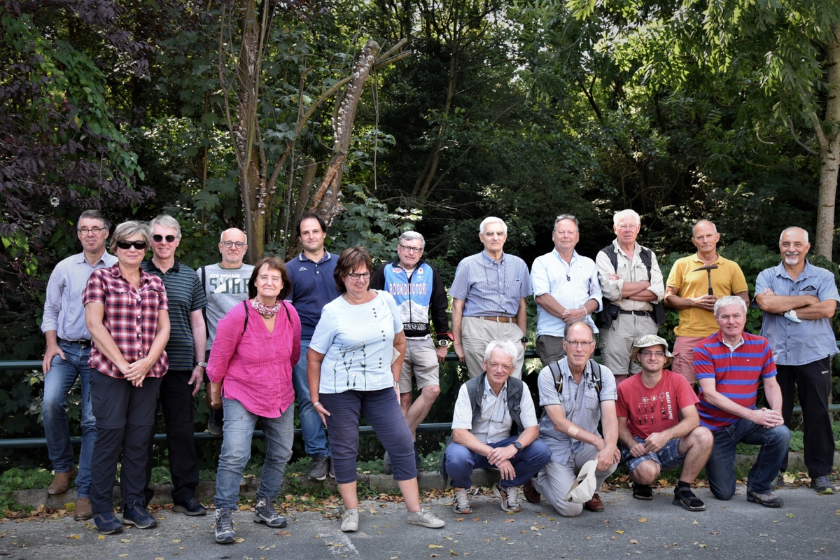 Foto di gruppo con una ventina di persone, dietro di loro piante