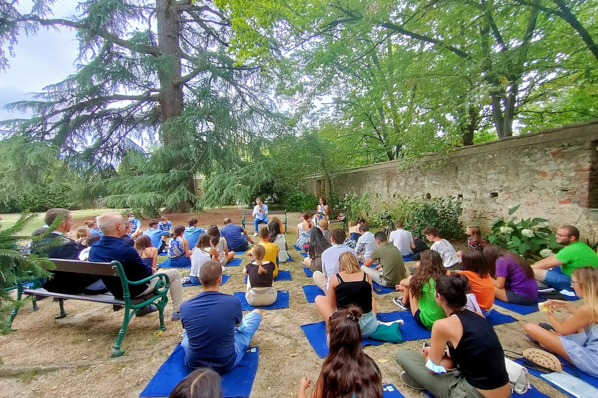 Conferenza di Fabio Fazio all'aperto, in un parco con alberi secolari: presenti molti giovani seduti su coperte sul prato
