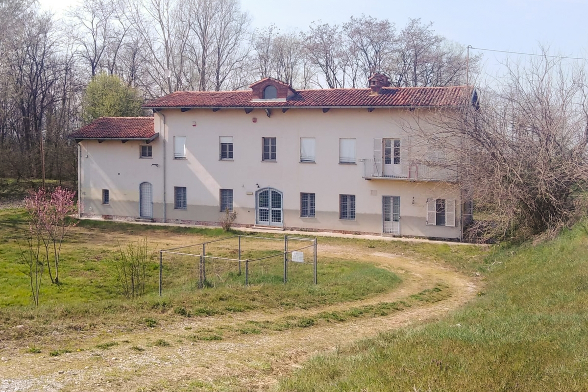 Caseggiato a due piani con pareti giallo chiaro e tetto in tegole rosse. intorno prati e alberi