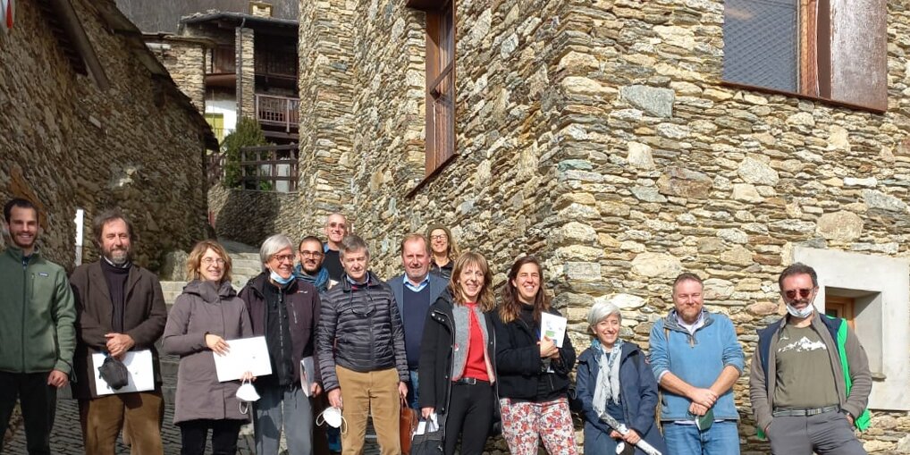 gruppo di persone davanti al centro Lou Pourtoun di Ostana, edificio in pietra a vista: quattordici tra uomini e donne