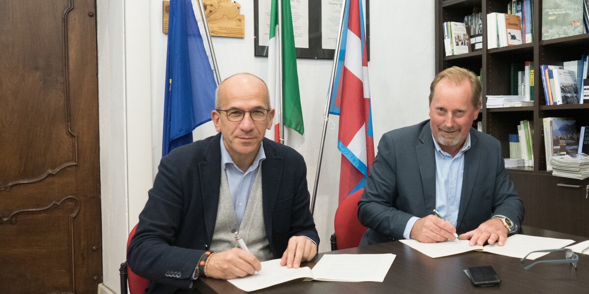 il presidente Oderda a sinistra e il presidente Miretti a destra seduti al tavolo firmano il protocollo d'intesa