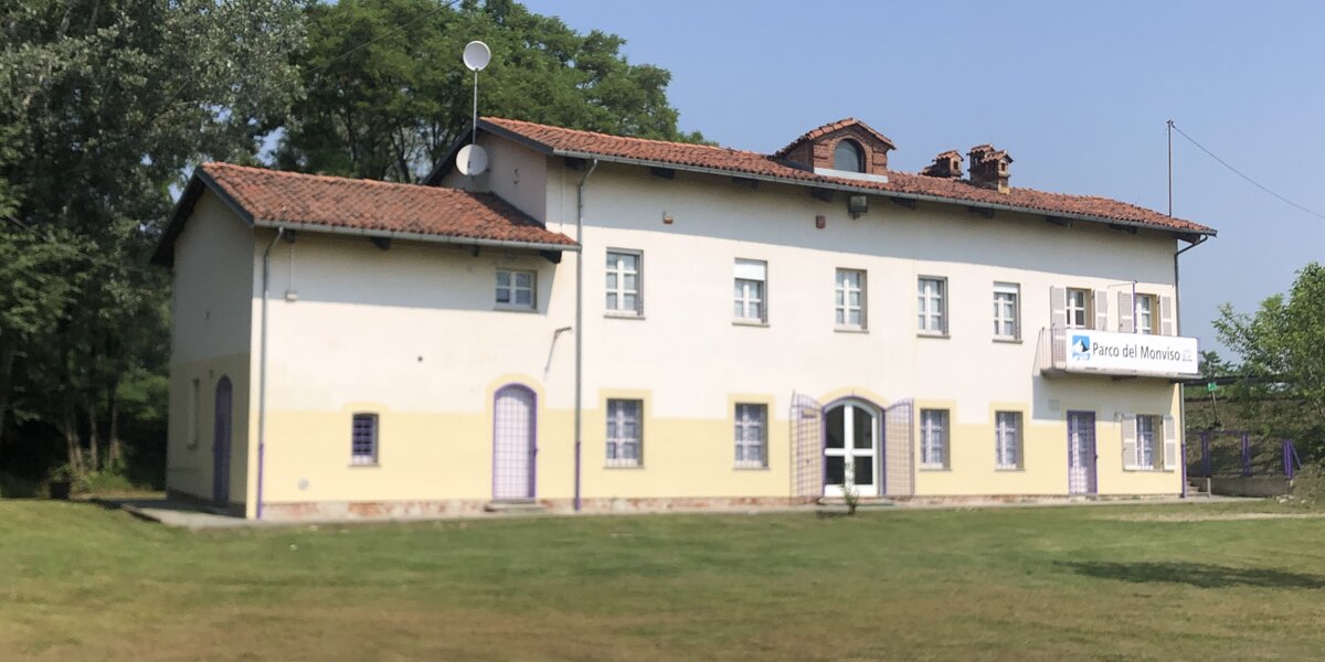 Un prato ben rasato con una struttura sullo sfondo: l'Ostello del Po