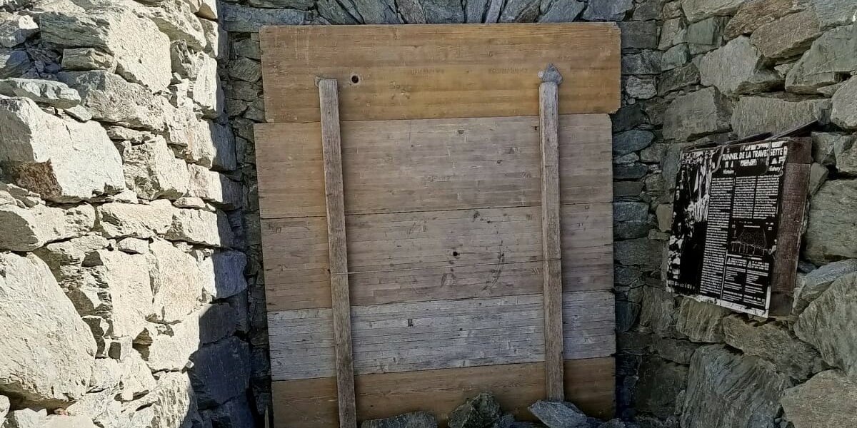 Assi di legno poste a chiudere il lato francese di Buco di viso; dietro le assi si vede l'architrave con arco in pietra. sulla destra si intravede il cartello informativo dedicato al traforo