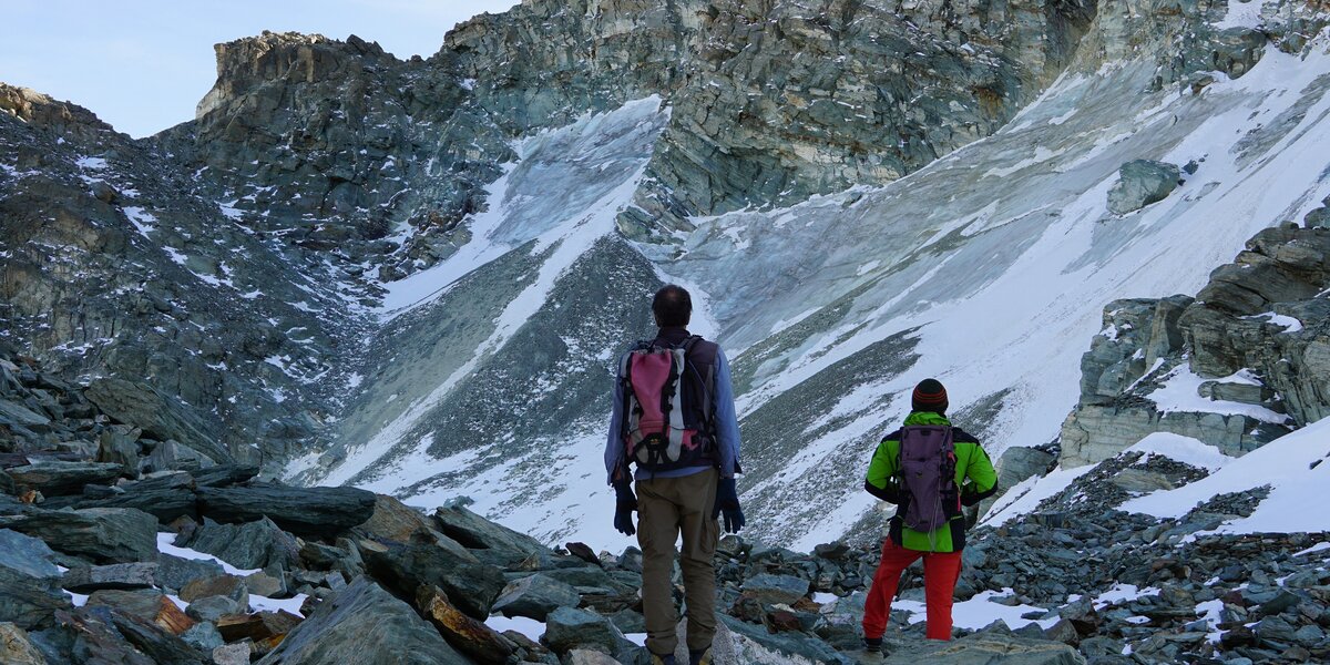 Due persone di spalle, in abito da escursione in montagna, guardano da poche decine di metri di distanza il ghiacciaio Coolidge
