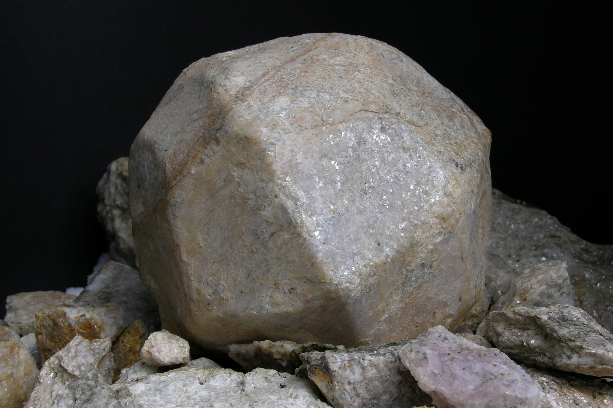 un cristallo di piropo di colore grigio su letto di pietre e sfondo nero