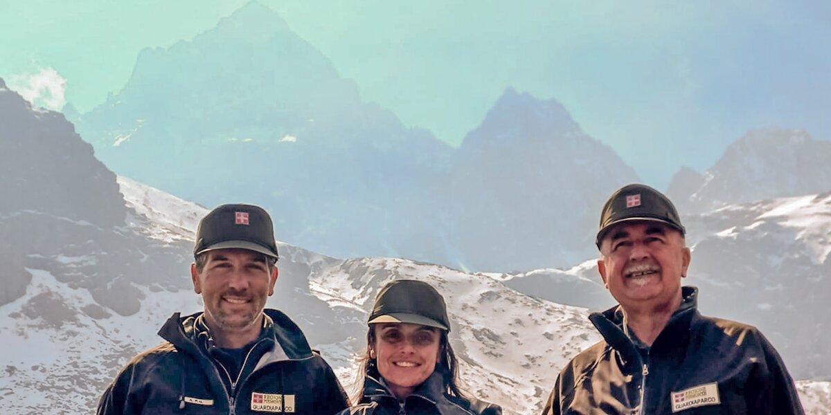Tre persone in primo piano, a mezzo busto, davanti ad uno sfondo nel quale spicca il Monviso