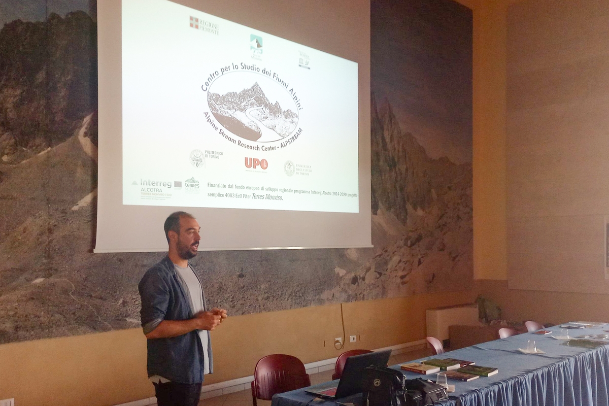 Alberto Doretto di Alpstream in piedi sulla sinistra dell'immagine mentre spiega al pubblico, non visibile in foto, le peculiarità del Centro per lo Studio sui Fiumi Alpini
