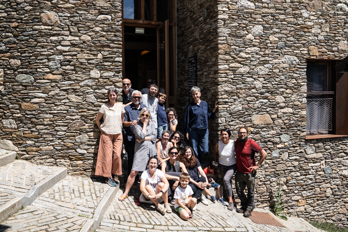 17 persone in piedi e sedute davanti all'ingresso di una struttura in pietra (il centro lou pourtoun) in una foto di gruppo. il terzo a destra è lo scrittore Amitav Ghosh, gli altri sono i componenti della cooperativa.