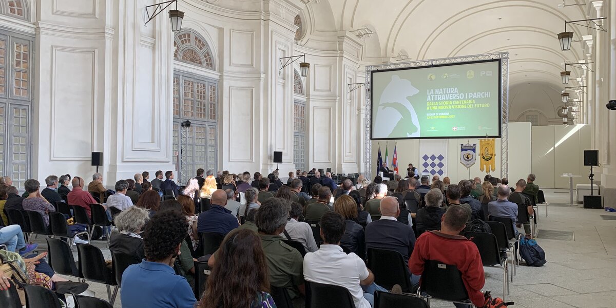 all'interno di una imponente sala (Sala della Citroniera della Reggia della Venaria Reale), molte persone sono sedute di fronte al palco dei relatori.