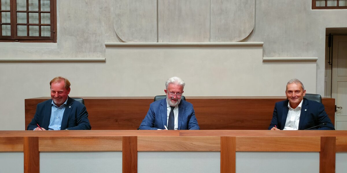 seduti ad un tavolo, i tre presidenti stanno firmando l'accordo