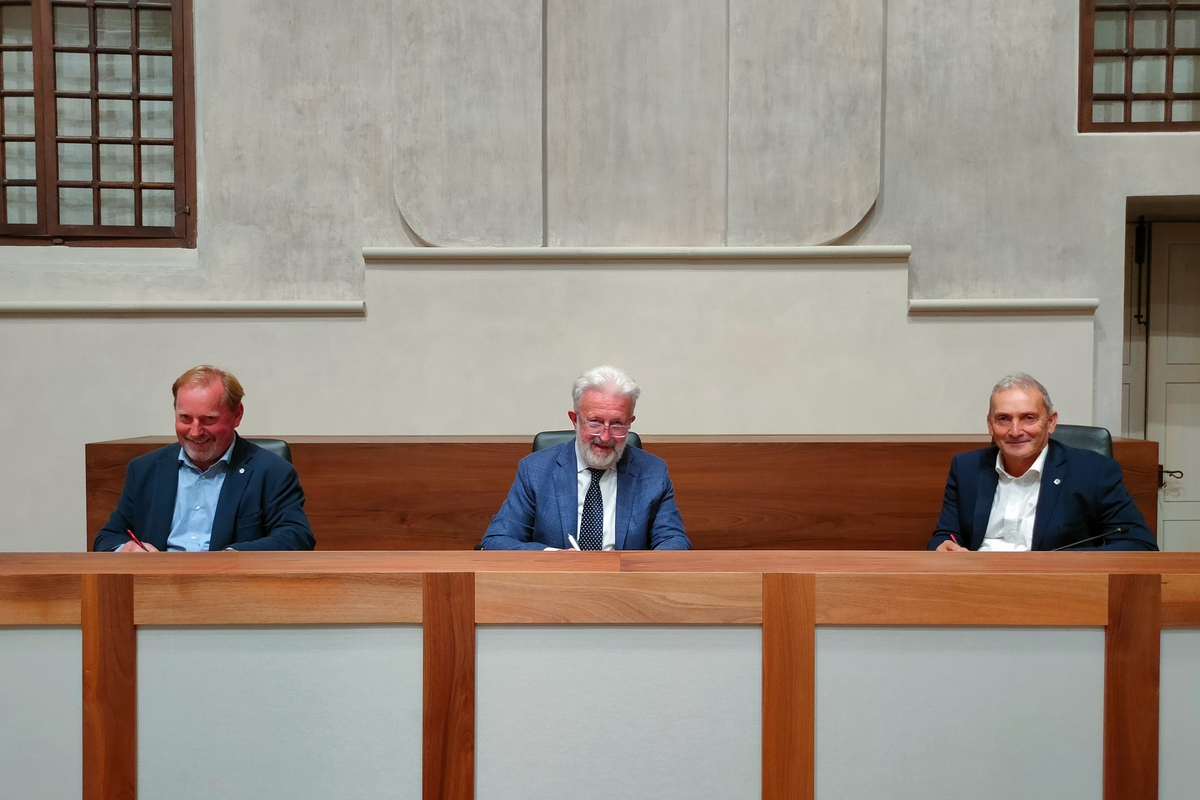 seduti ad un tavolo, i tre presidenti stanno firmando l'accordo