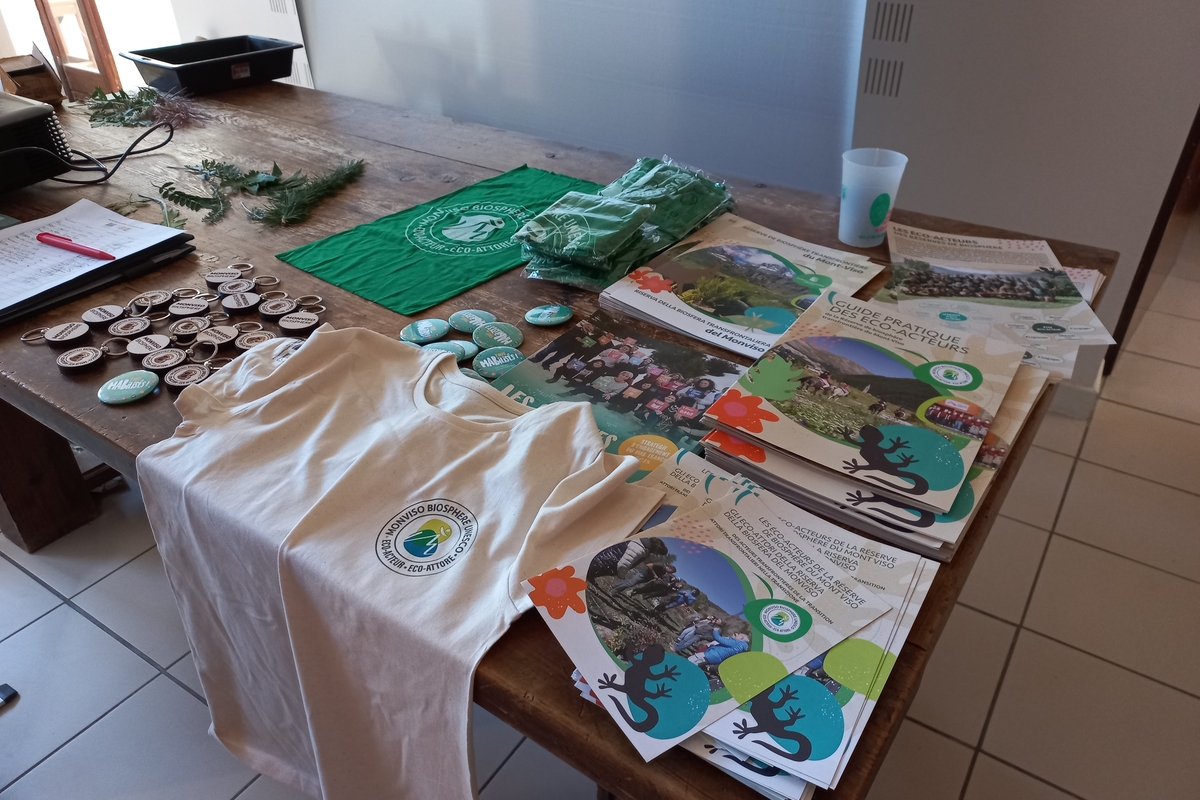 su un tavolo gadget con il logo degli eco-attori: magliette, spille, depliant