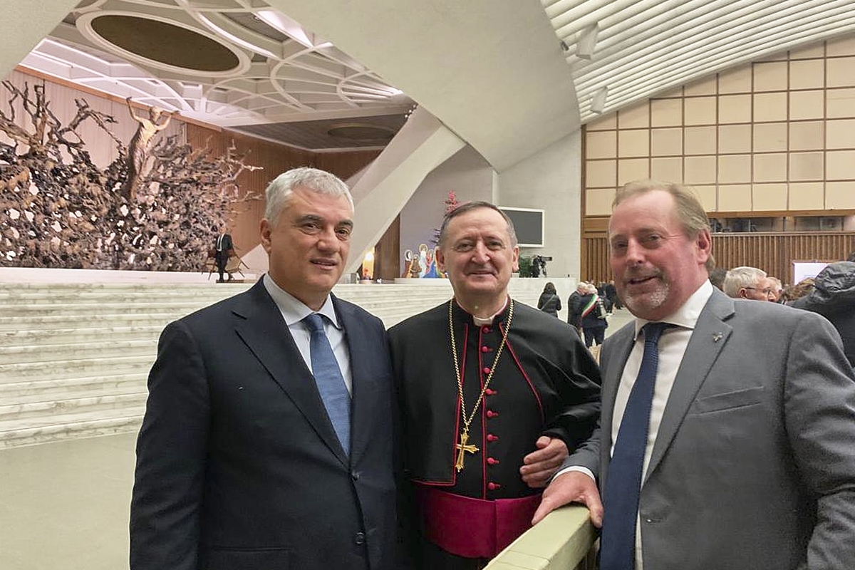 Tre persone in primo piano: al centro c'è il vescovo di Saluzzo e ai suoi lati i due presidenti delle Riserve MaB Unesco del Monte Peglia, a sinistra, e del Monviso, a destra. Sullo sfondo si riconosce la sala Paolo VI in Vaticano.