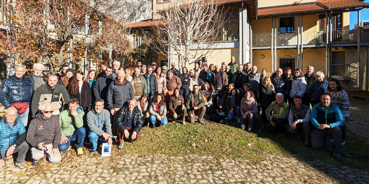 foto di gruppo dei circa 100 partecipanti all'incontro, posti a semicerchio in un'area all'aperto sul retro della sede dell'Ente di Gestione delle Aree protette delle Alpi Marittime