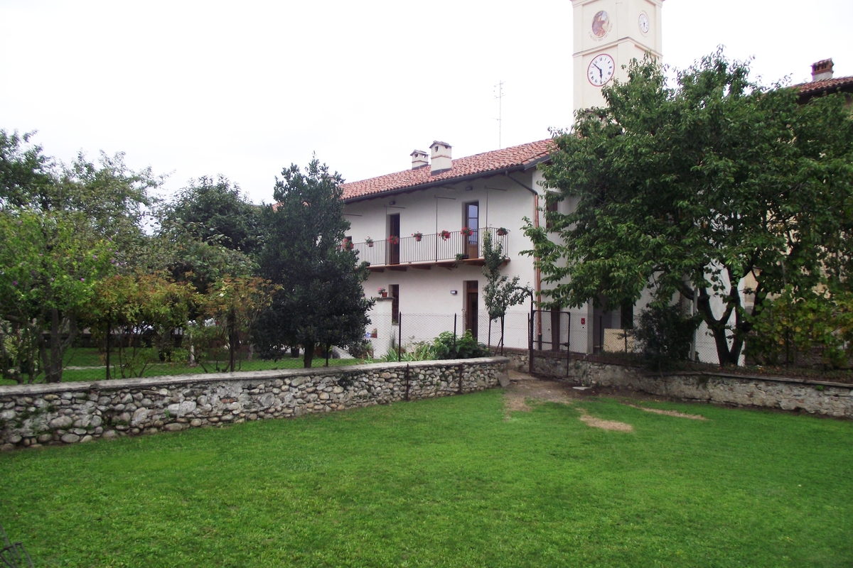 Facciata della struttura ricettiva immersa nel verde con alle spalle il campanile della chiesa di Monastero.
