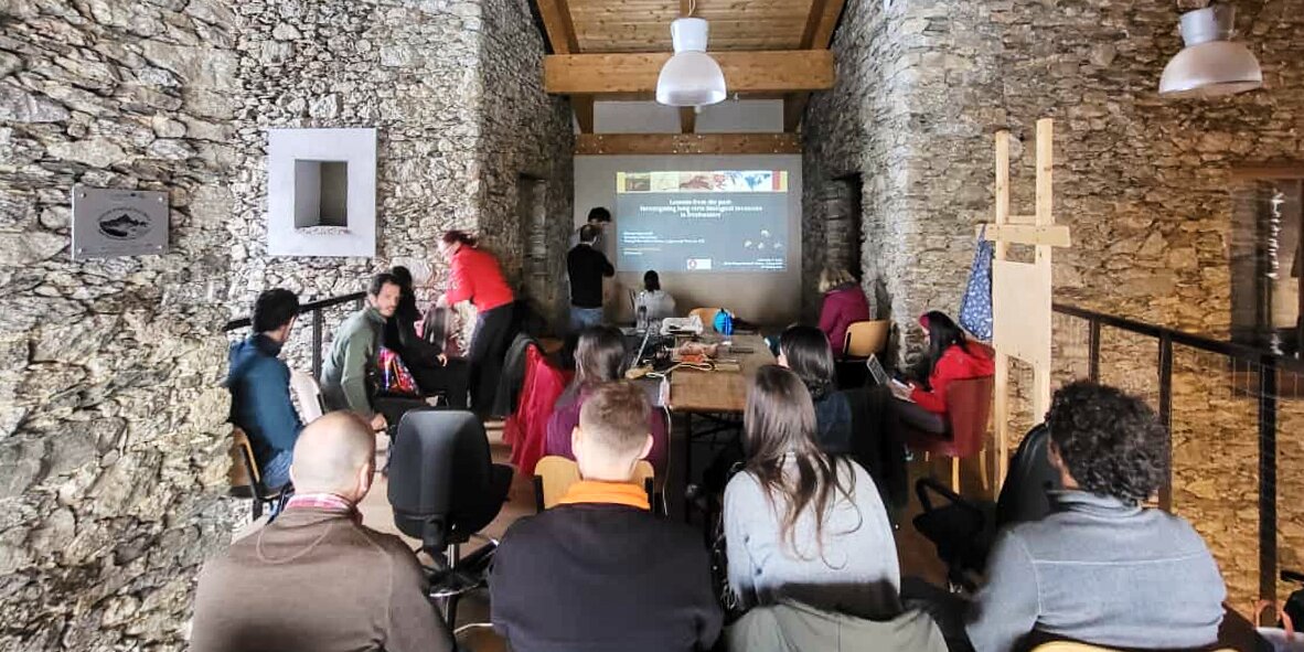 un gruppo di persone sedute di fronte a uno schermo che proietta diapositive di lavoro