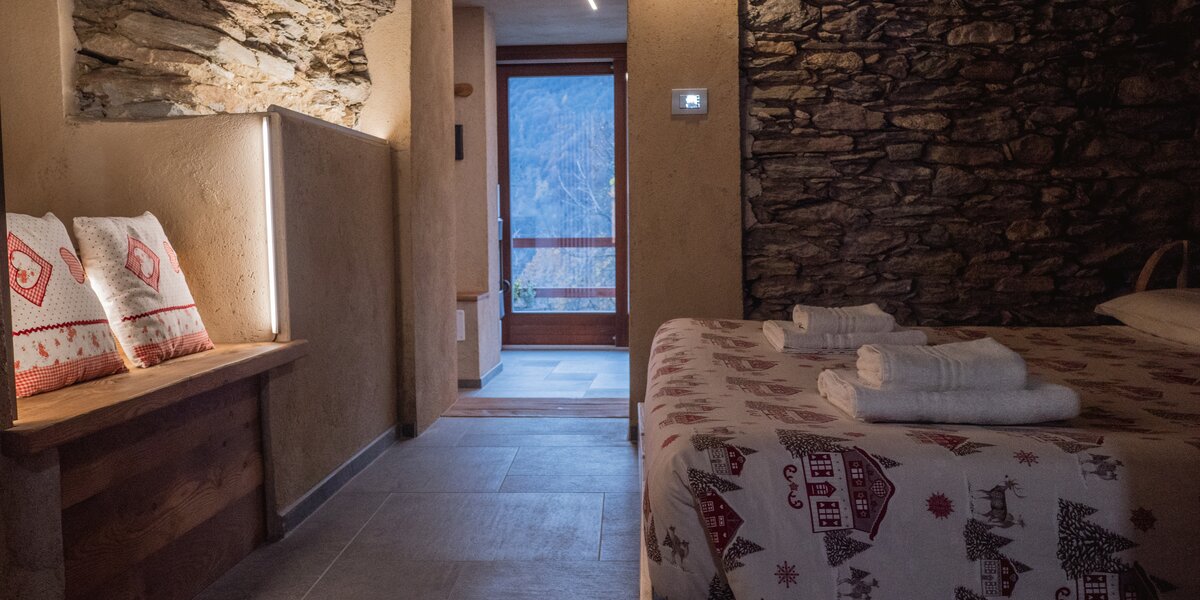 l'interno della camera della struttura ricettiva descritta nell'articolo: la foto inquadra sulla destra il letto, di fronte c'è la porta che si apre sul bosco antistante.