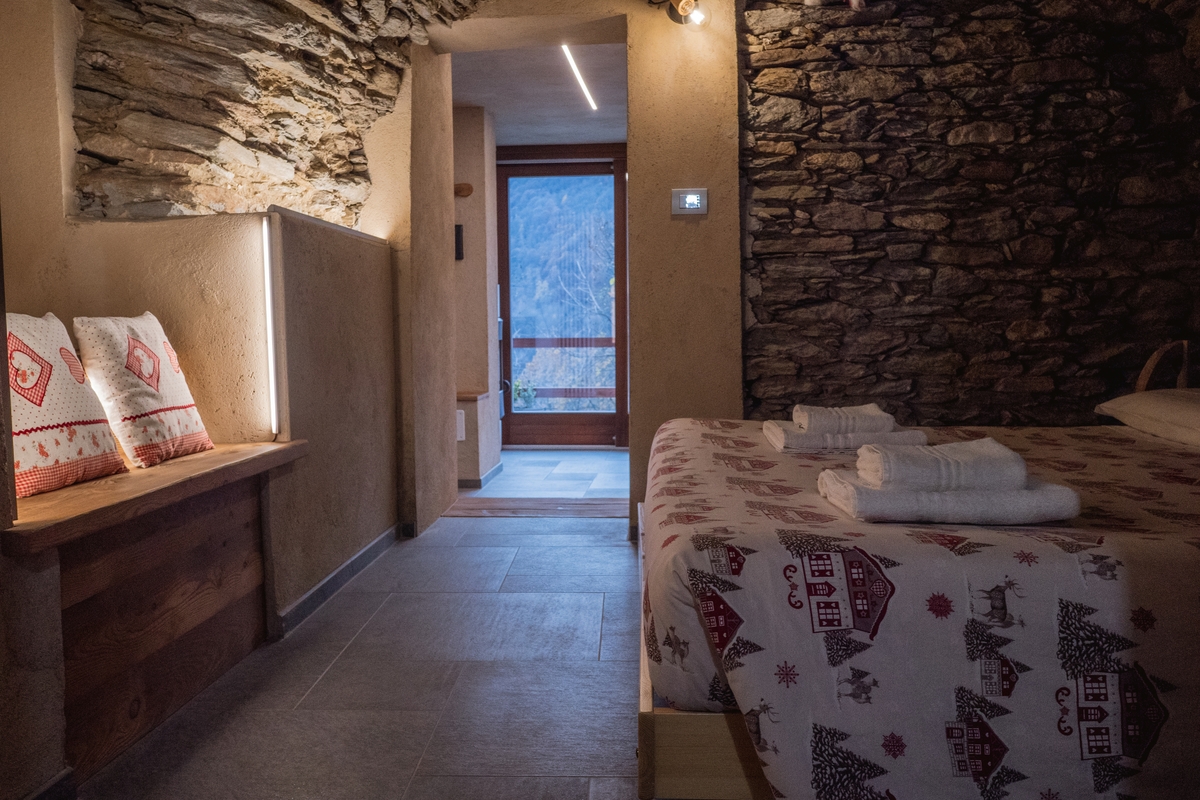 l'interno della camera della struttura ricettiva descritta nell'articolo: la foto inquadra sulla destra il letto, di fronte c'è la porta che si apre sul bosco antistante.