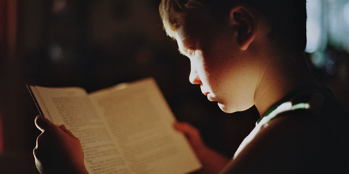 bambino che legge in penombra