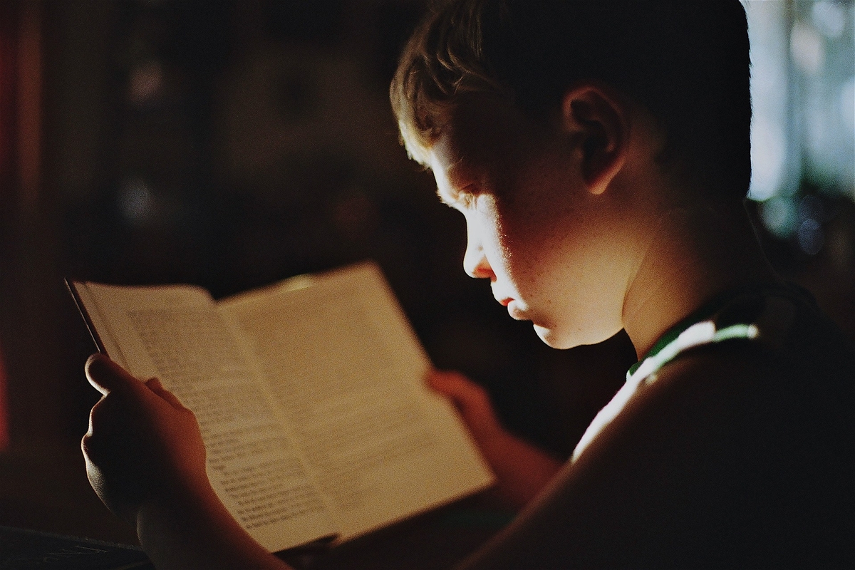 bambino che legge in penombra