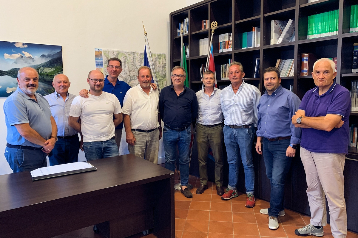 foto di gruppo nell'ufficio di presidenza del Parco del Monviso: dieci uomini dietro ai quali si intravedono le bandiere dell'Unione Europea, dell'Italia e del Piemonte e una libreria.