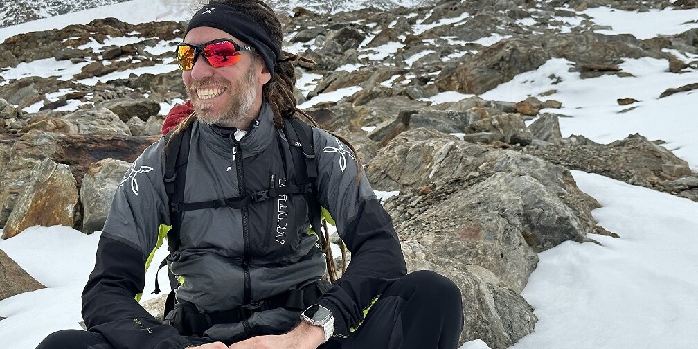 Simone Salvagnin in una foto all'aperto, con abbigliamento invernale e seduto su una roccia intorno alla quale c'è neve