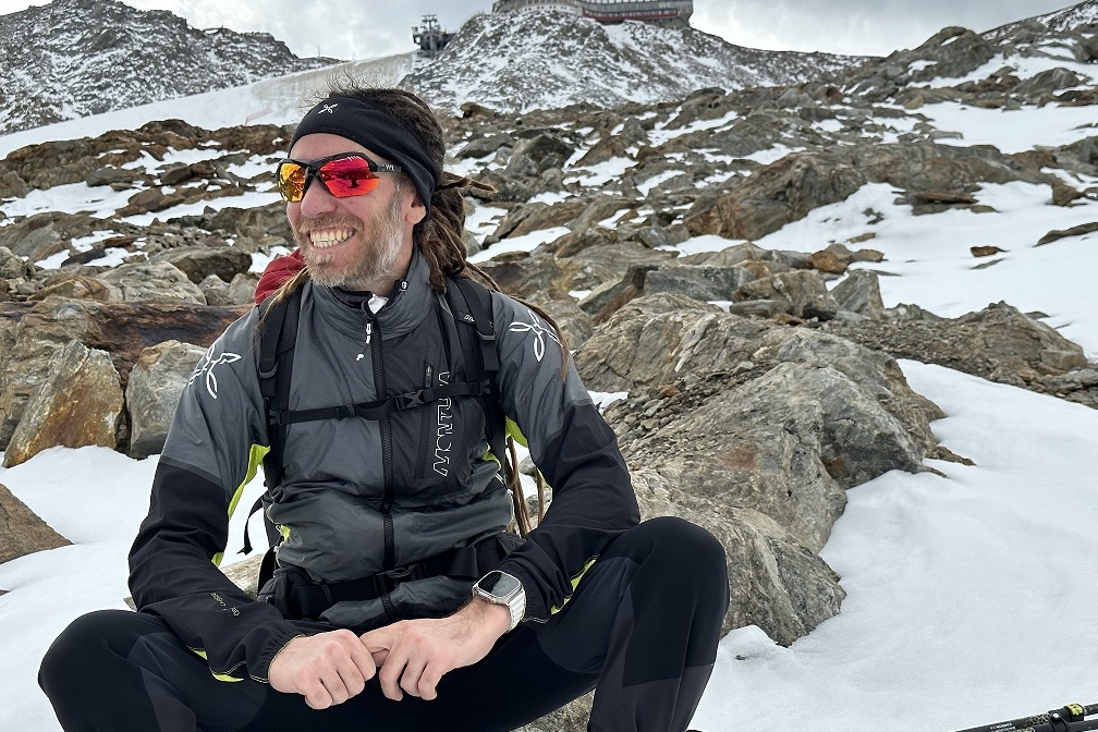 Simone Salvagnin in una foto all'aperto, con abbigliamento invernale e seduto su una roccia intorno alla quale c'è neve