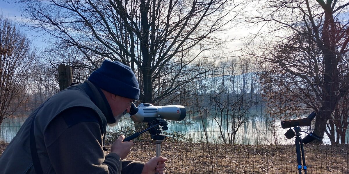 personale del Parco del Monviso impegnato nelle osservazioni: sulla sinistra della fotografia si vede un operatore chino su un cannocchiale rivolto verso un'area lacustre, che si estende sulla parte destra dell'immagine