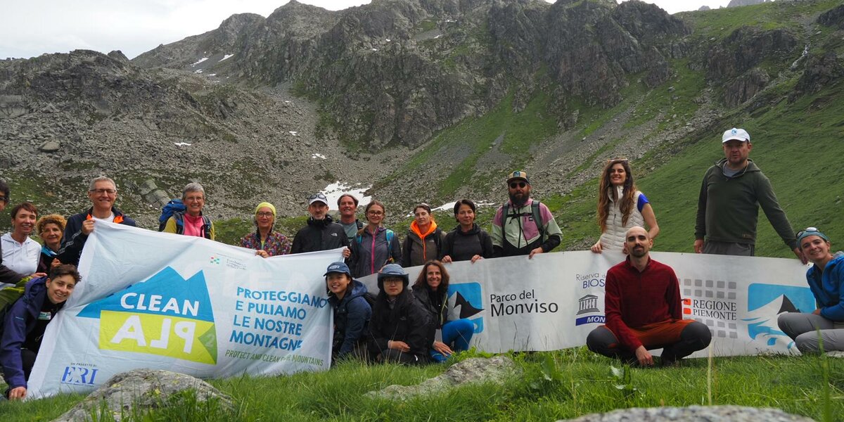 foto di gruppo dei partecipanti a una delle due escursioni citate nel testo. I partecipanti sorreggono gli striscioni dell'iniziativa, quello di CleanAlp e quello del Parco del Monviso.