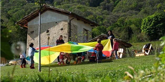 bambini giocano con stoffe colorate creando un girotondo in un prato
