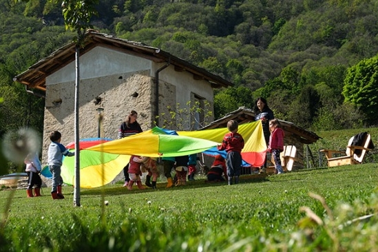 bambini giocano con stoffe colorate creando un girotondo in un prato