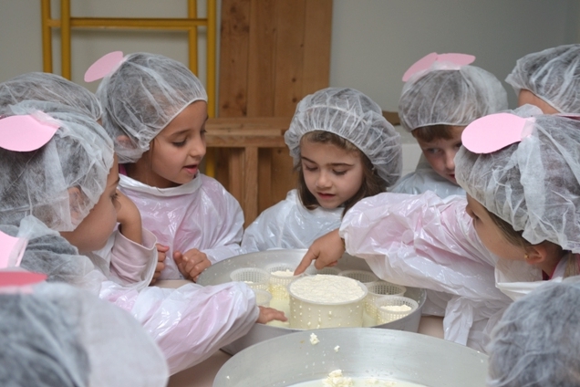 bambini con camici e cuffiette manipolano del formaggio
