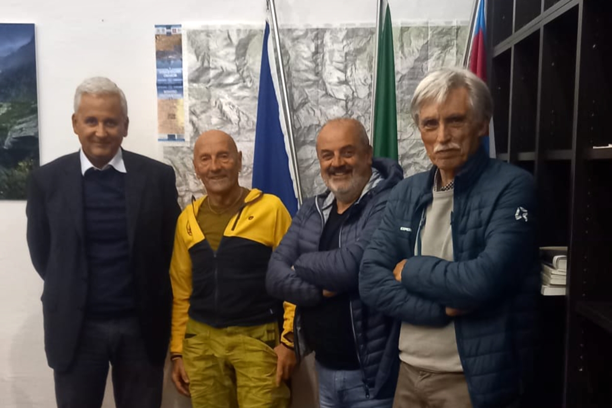 quattro uomini in piedi davanti a una parete con una carta topografica e bandiere.