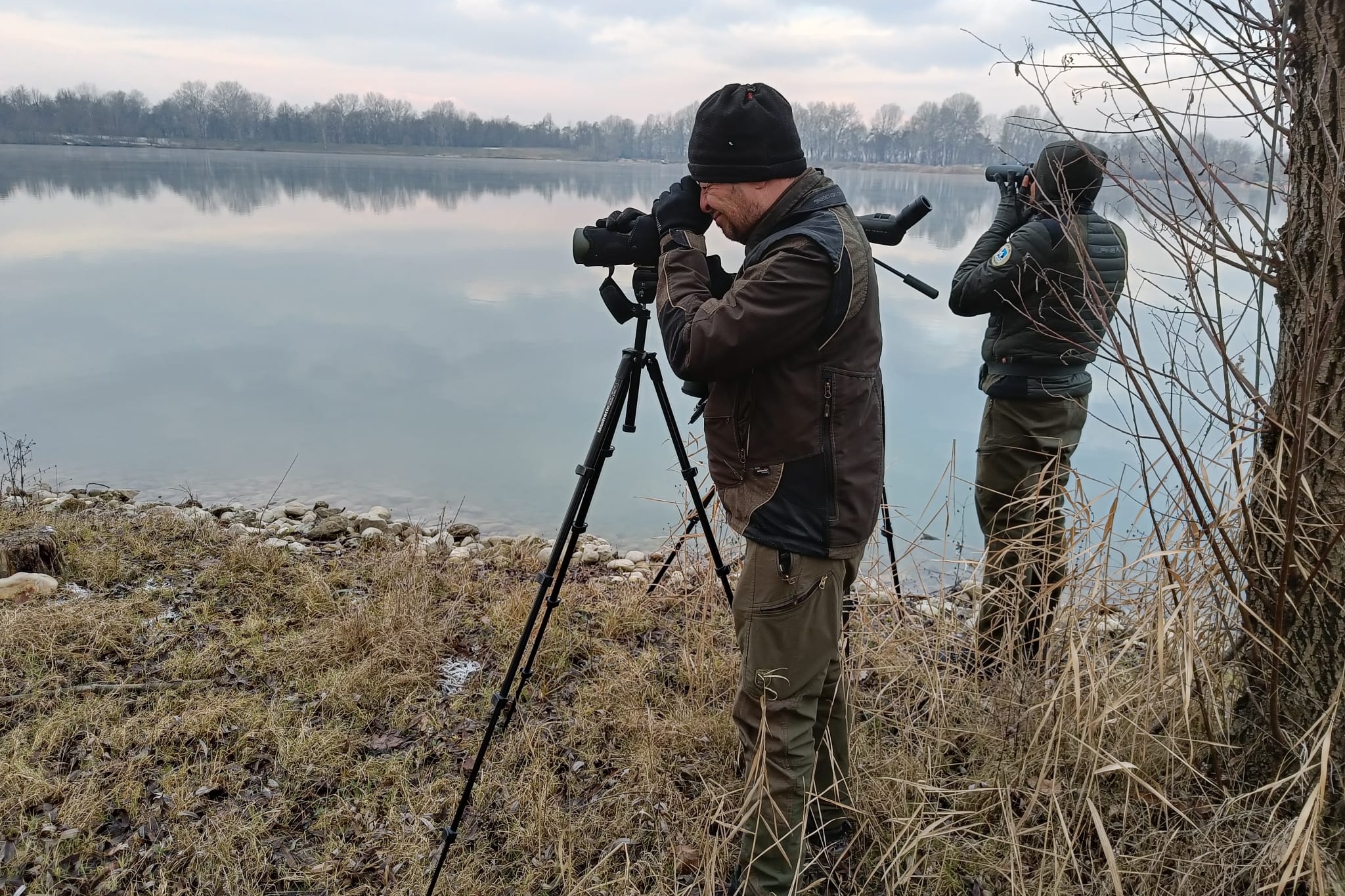 due guardiaparco sono impegnati in osservazioni al binocolo in una area lacustre.
