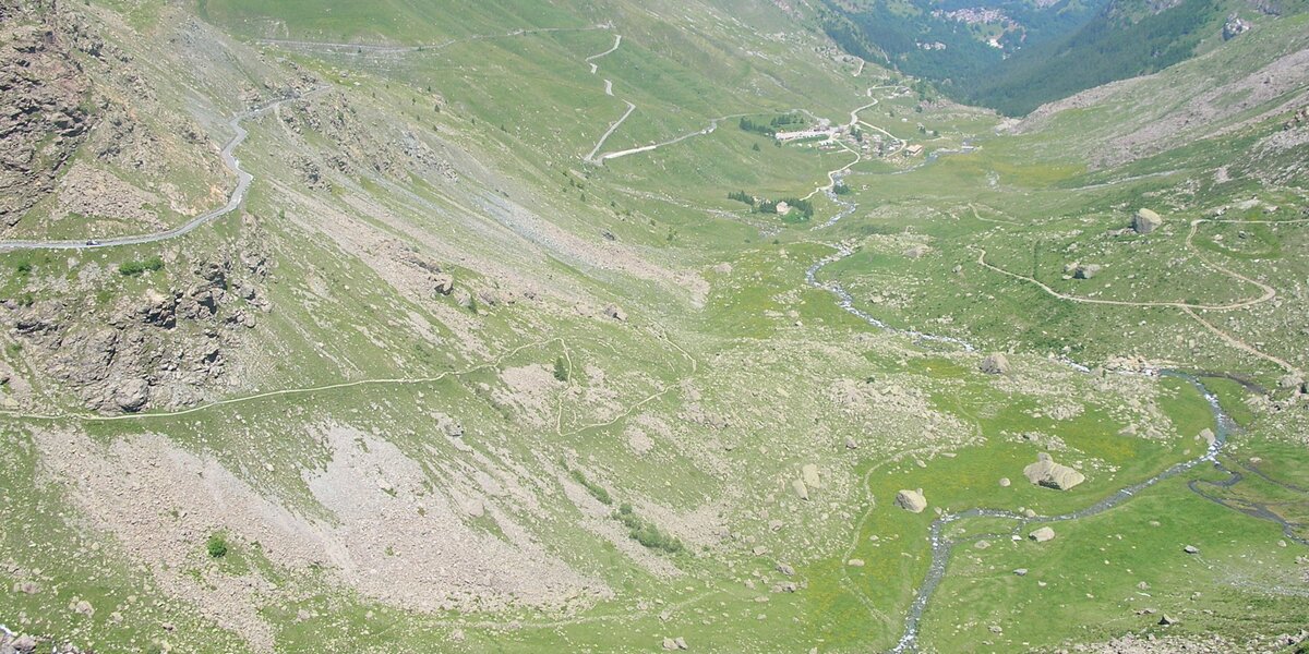 Una vista aerea che mostra una strada tortuosa che sale su un ripido pendio di una montagna erbosa in una valle.
