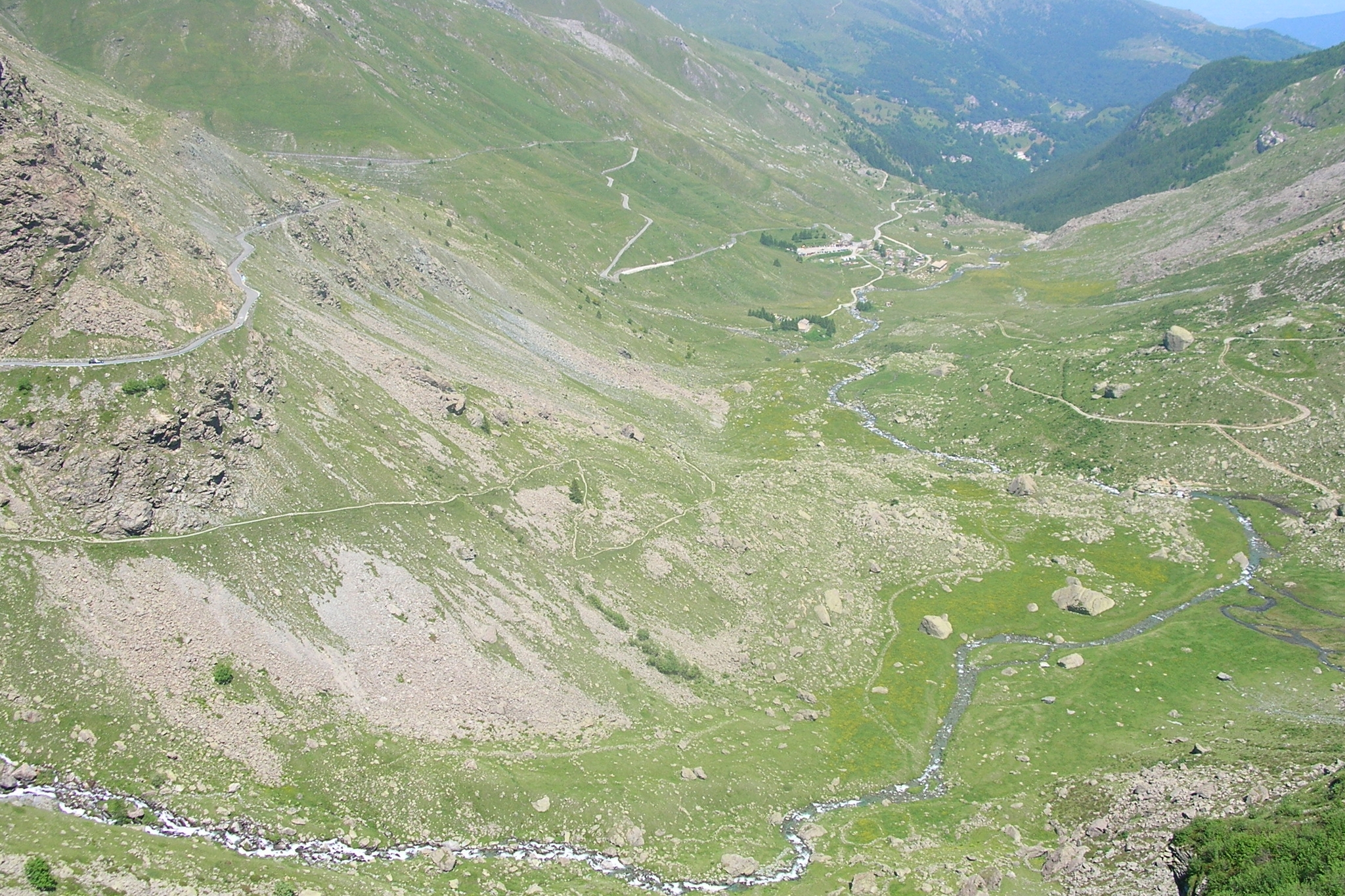 Una vista aerea che mostra una strada tortuosa che sale su un ripido pendio di una montagna erbosa in una valle.