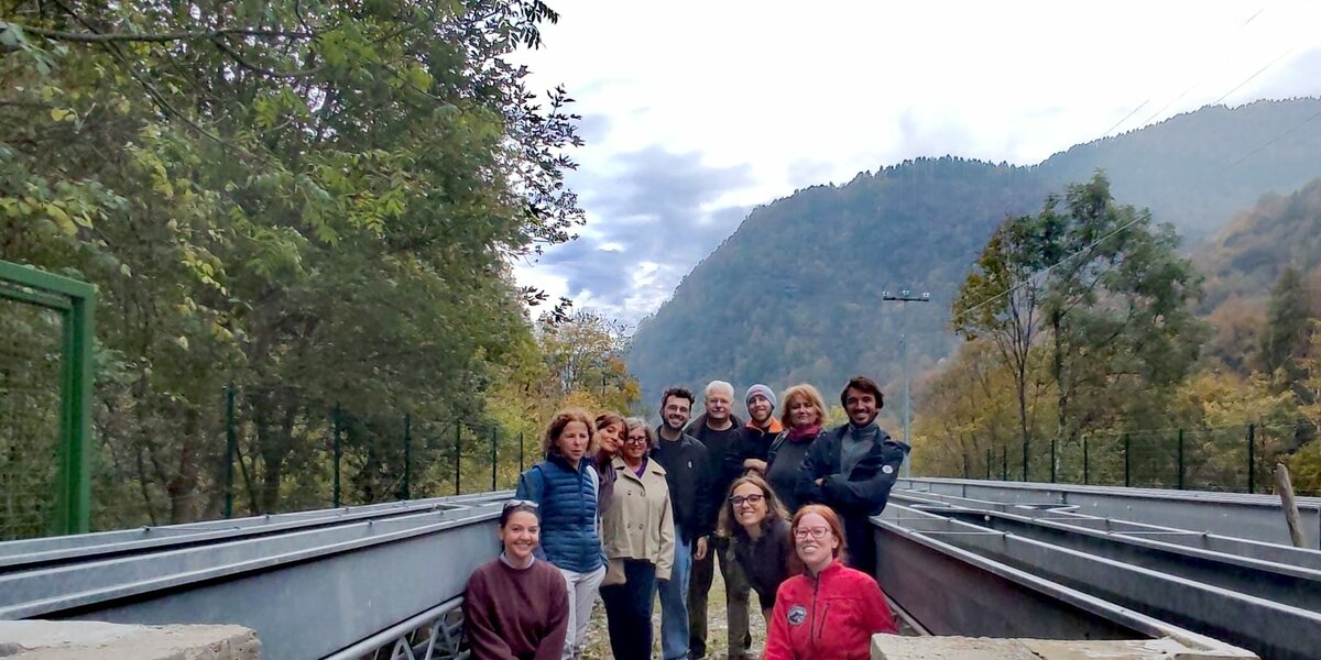 gruppo di persone tra i corpi fluviali artificiali di Ostana