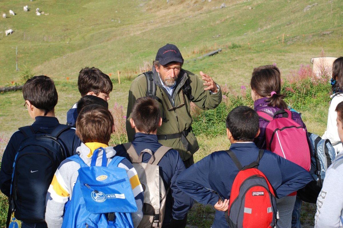Un accompagnatore naturalistico spiega ad un gruppo di bambini l'ambiente montano circostante